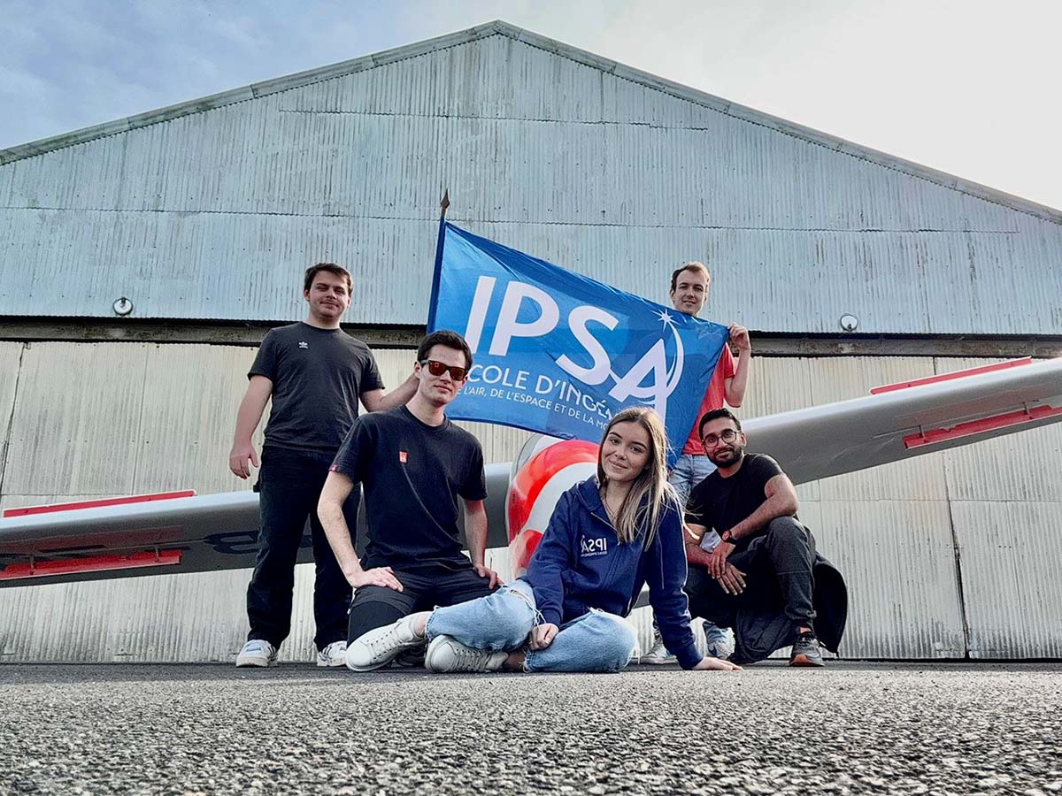 Groupe d'étudiants posent devant un avion et le drapeau de l'IPSA